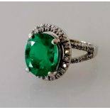 An oval emerald and diamond cluster ring, 10 x 7.9 x 5.35 mm weighing a calculated 2.50 carats