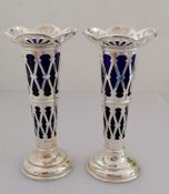 A pair of Edwardian pierced silver vases with trellis pattern, blue glass liners on stepped bases by