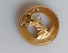 A gold gem-set circular brooch with rope-twist rim and applied carved figure to centre, stamped 14k