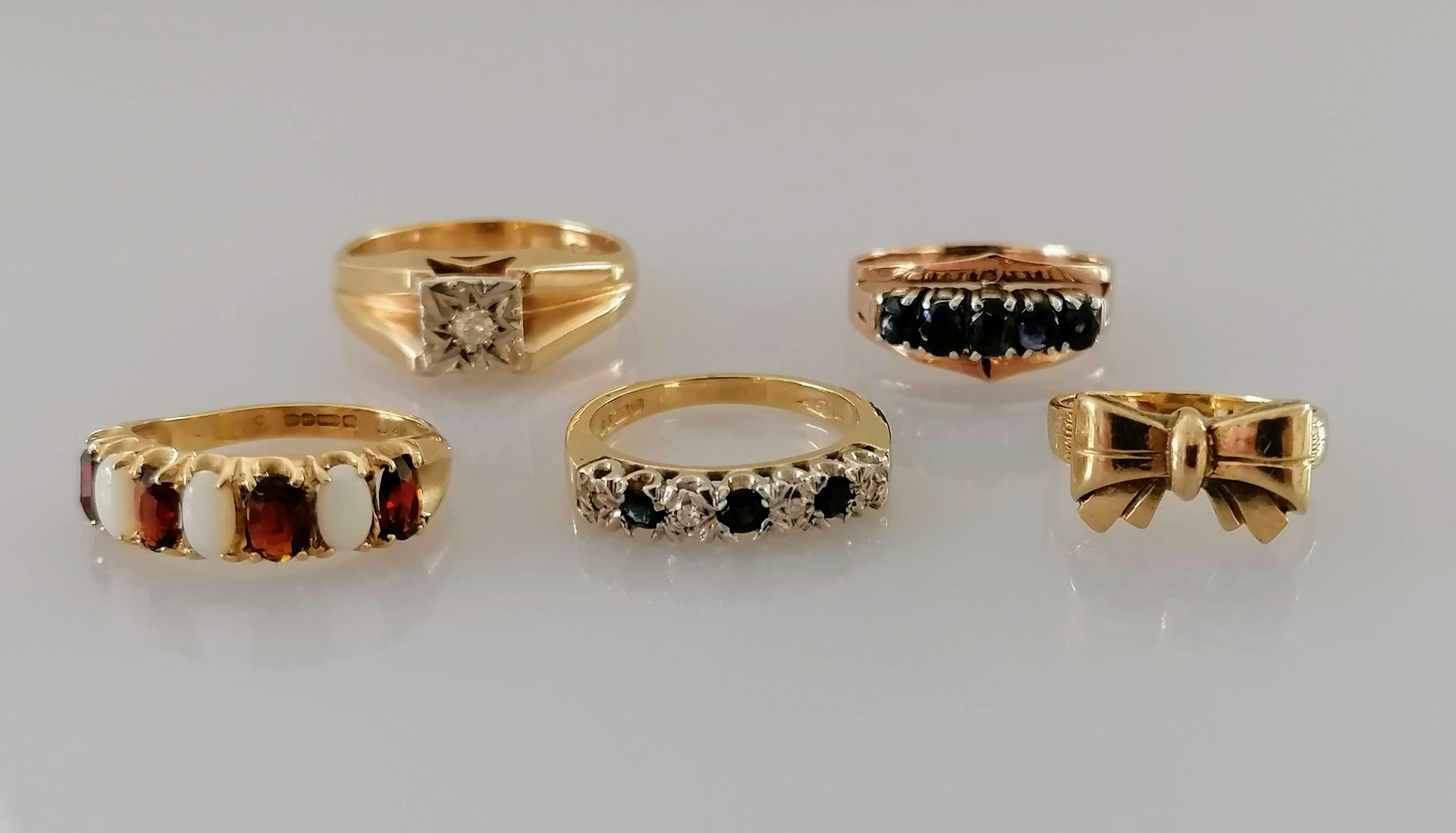 A selection of four gold gem-set rings and one other, smallest J, largest M, all hallmarked or