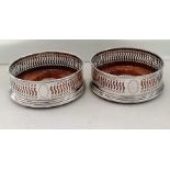 A pair of silver bottle coasters with pierced decoration, vacant cartouches, on stepped bases by W I
