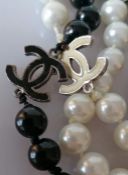 A Chanel black and white bead necklace with six black and white logo links, 160 cm