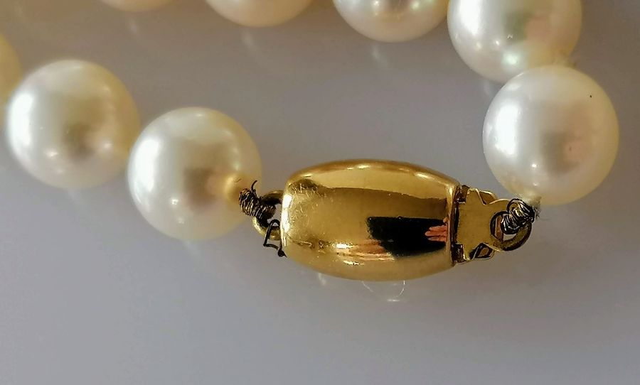 A single row of sixty Akoya cultured pearls measuring from 6.5mm to 7mm on a yellow gold barrel clas