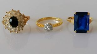 An oval sapphire (7mm x 5mm) cluster ring surrounded by two tiers of brilliant-cut white sapphires o