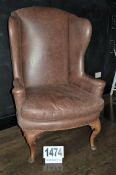 A Brown Leather Upholstered Wing Back Arm Chair with Brass Studded Seams on Carved Wooden Legs