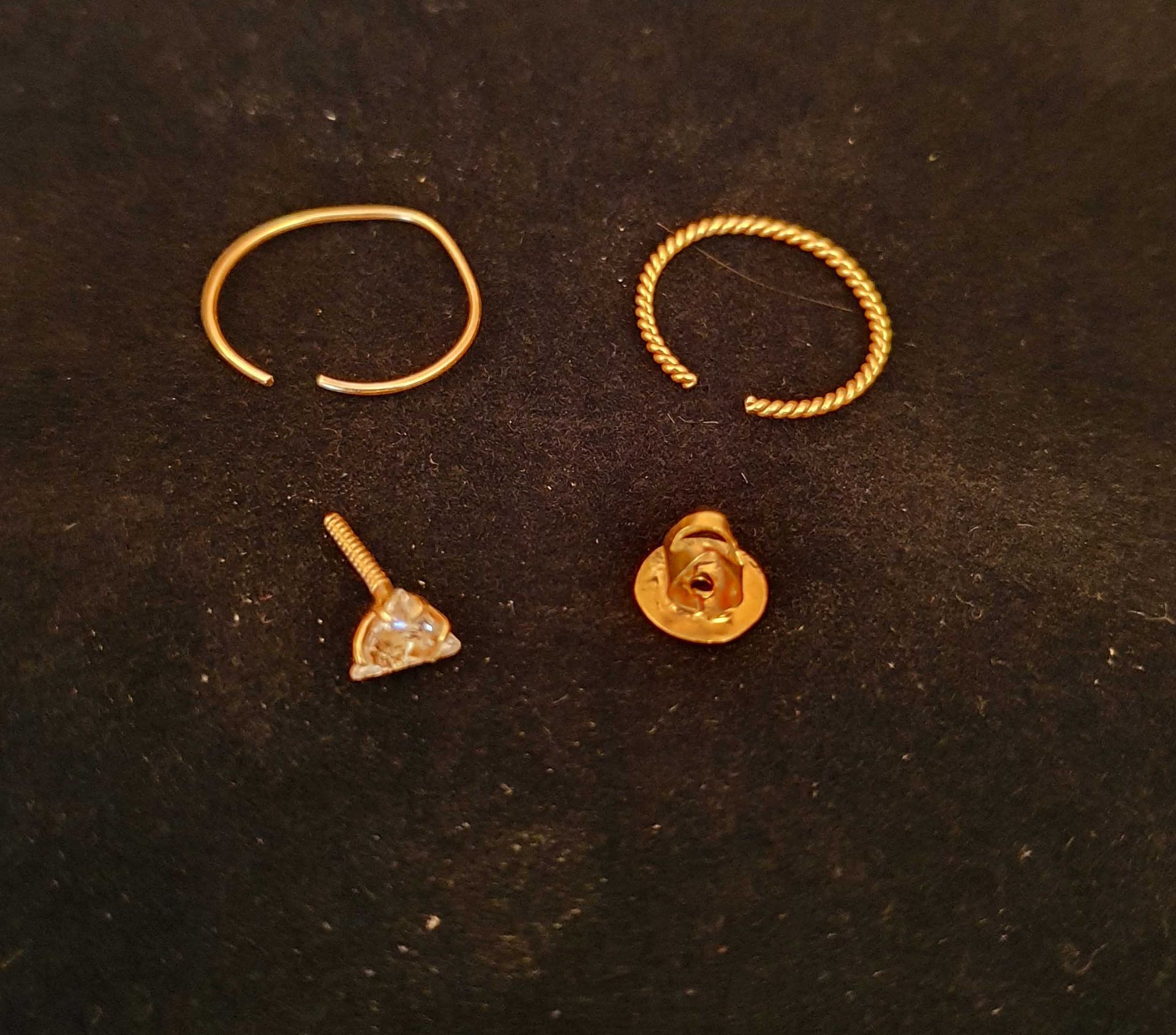 A Set of 3 Nose Piercings Comprising: 1 Nose Piercing Trillion Shaped Stone with Gold Setting, 0.