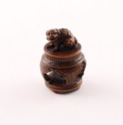 <de>NETSUKE SHISHI AUF EINEM TISCH, Buchsbaum, das Fabeltier sitzt mit geöffneten Maul auf einem vie