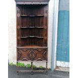 Antique oak corner cupboard with shelving on barley twist legs and stretchers and carved detail to