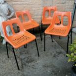 Four mid 20th century orange plastic stacking chairs with tubular metal frames in good used