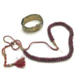 Strand of garnet beads on a silk cord (worn) t/w ethnic bangle