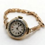 Ladies 18ct gold manual wind diamond set bezel wristwatch on a 15ct marked gold sprung bracelet -