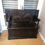 Circa 1920's dark oak monks bench with carved detail to the front panels and top with under seat