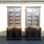 A pair of late victorian carved oak glazed front bookcases with four adjustable height shelves