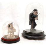 2 small glass domes on wooden bases - largest has figure of gentleman reading - 14cm high & has chip