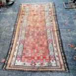 Antique wool coral grounded rug 120cm x 208cm. Some wear