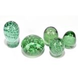 Five Victorian green glass dump weights comprising three examples with internal bubbles and two with