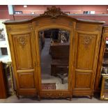 A large French three drawer breakfront wardrobe with scrolling pediment above bevelled central