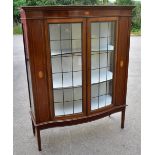 An Edwardian inlaid mahogany serpentine fronted display cabinet, the pair of leaded glazed doors