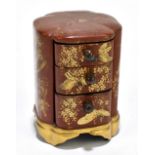 A Japanese Meiji period red and gold lacquered three drawer chest decorated with birds in flight and