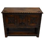 An early 20th century carved oak side cabinet, the moulded top above central carved panel flanked by