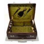 An early 20th century leather cased travelling vanity case, enclosing part fitted interior with