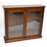 A late Victorian bookcase, the pair of glazed doors enclosing shelves, raised on bracket feet, width