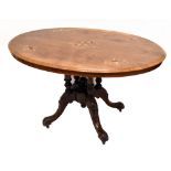 A late Victorian walnut inlaid oval loo table, raised on carved square section outswept scrolling