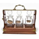 BETJEMANN'S PATENT; an oak tantalus with silver plated mounts, housing three cut glass decanters,