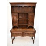 A 1920s Jacobean style oak dresser, the raised back with three open shelves and two panelled