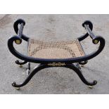 An early 20th century ebonised window seat with scrolling frame and bergère caned panel.