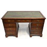 A reproduction oak pedestal desk, with leather inset top above an arrangement of nine drawers, on