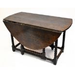 An 18th century oak oval drop-leaf gateleg dining table raised on bobbin turned and block supports