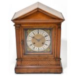 A late 19th century walnut mantel clock, the brass face set with silvered chapter dial with both