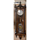 A walnut veneered and ebonised Vienna style wall clock with circular dial and Roman numerals,