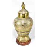 A large Eastern brass clad metal urn and cover on associated wooden stand, height approx 72cm.