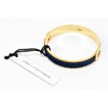 DIANE VON FURSTENBERG; a gold tone metal and blue denim inlaid bracelet with original tag, size