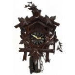 A Black Forest cuckoo wall clock, with stag head surmount above the black chapter ring bearing Roman