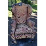 A 19th century wing back armchair raised on mahogany cabriole front legs with concave front,
