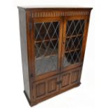 A reproduction oak Priory style bookcase, with leaded glazed doors above a pair of panelled doors