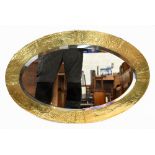 An Arts & Crafts style sheet brass framed wall mirror with planished decoration surrounding the