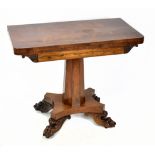 An early 19th century rosewood fold over tea table, with column and platform, on carved paw feet,