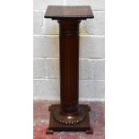 An early 20th century oak jardinière stand with square sectioned top above fluted cylindrical
