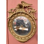 A Regency gilt framed wall mirror with eagle finial above circular main section.