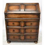 A 1950s oak bureau, with fall front enclosing a fitted interior, with three long drawers and