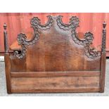 A French carved walnut serpentine bed head with scroll detailing, height 124cm.