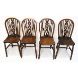 A set of four early 20th century beech and ash wheel back country kitchen chairs, with solid seats