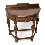 An early 20th century oak demi-lune side table with carved gallery back and central drawer, on