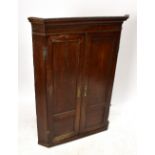A George III oak hanging corner cupboard, with paneled doors enclosing curved shelves, height 121cm,