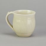 DEREK EMMS (1929-2004); a porcelain mug covered in pale yellow celadon glaze with incised