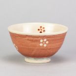 MOTOKO WAKANA (born 1962); a stoneware bowl washed in copper red glaze with wax resist decoration,